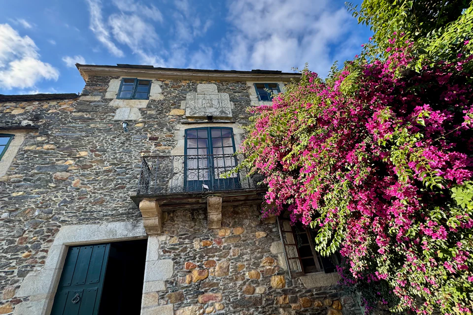 Casa de piedra con balcón y buganvilla en flor
